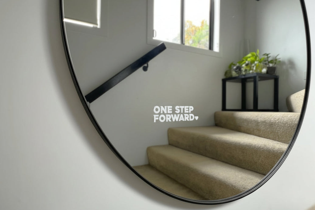 Round mirror on a wall reflecting a staircase and room interior.